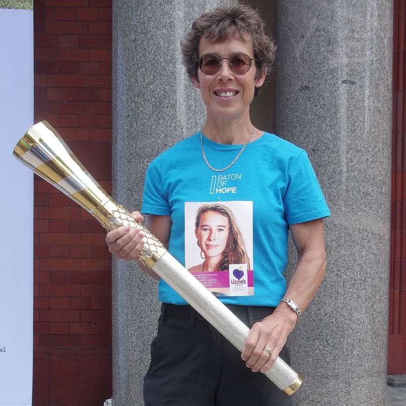Wearing a blue Baton of Hope t-shirt, Hilary holds the gold and silver baton.